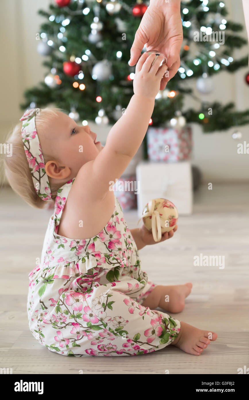 Baby girl in front of Christmas tree with gifts and decorations Stock Photo