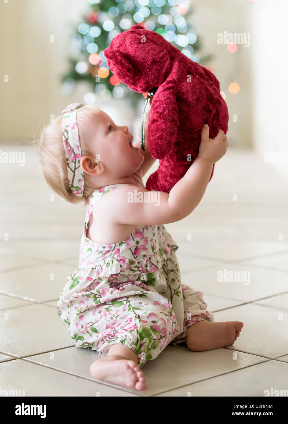 Baby girl playing with red teddy bear at Christmas time Stock Photo