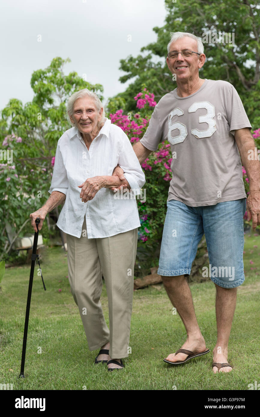 Man helping happy senior lady walking in garden Stock Photo