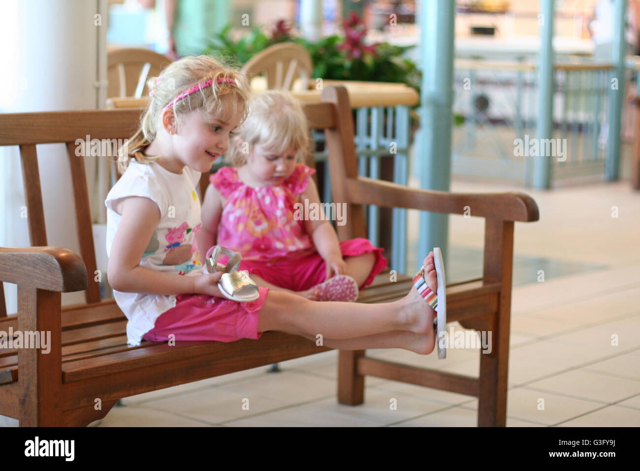Little girls, children kids  sitting on a bench having fun playing together Stock Photo