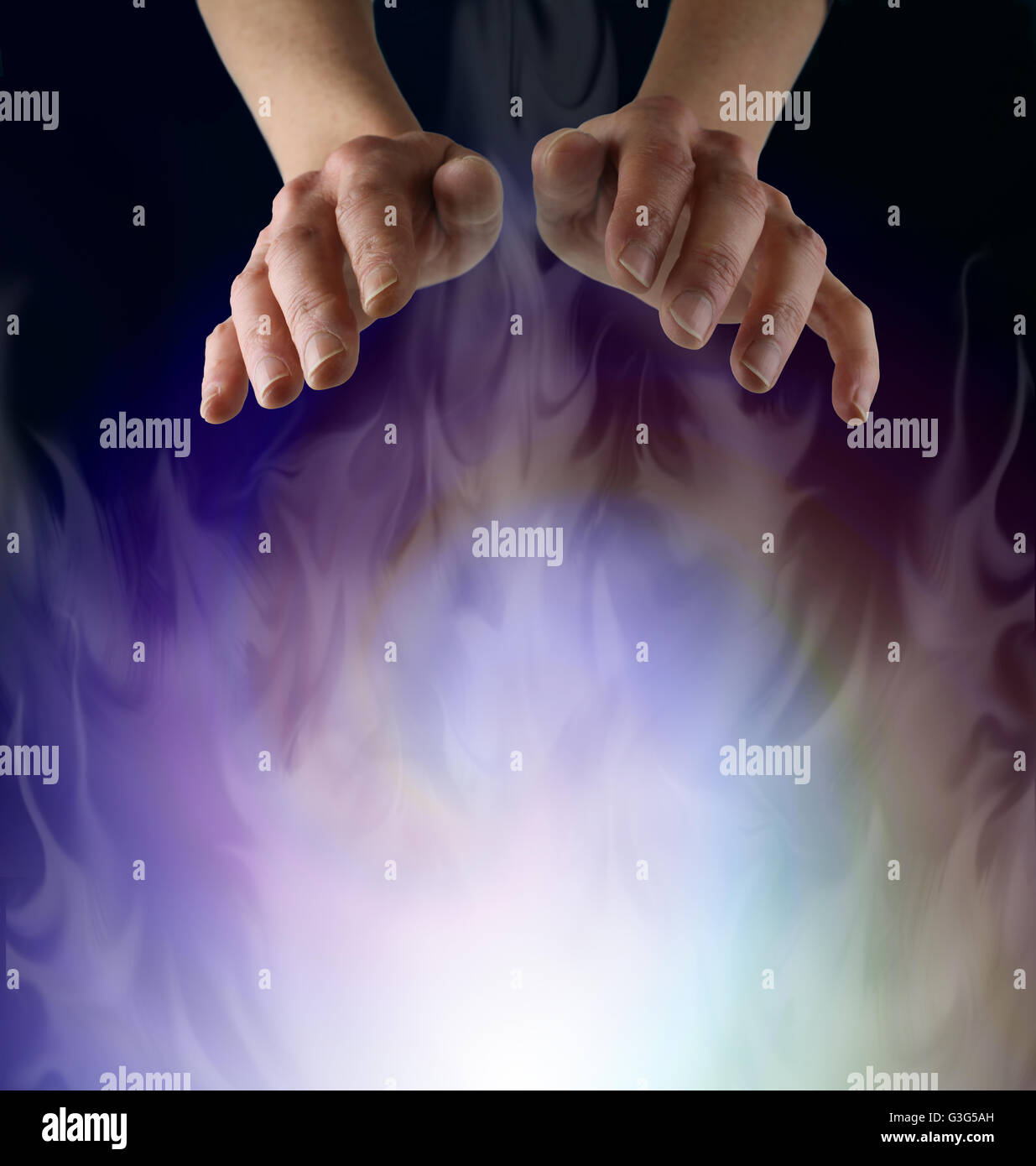Spirit Matter - Pair of female hands hovering over a misty ethereal energy field on a black background with plenty of copy space Stock Photo