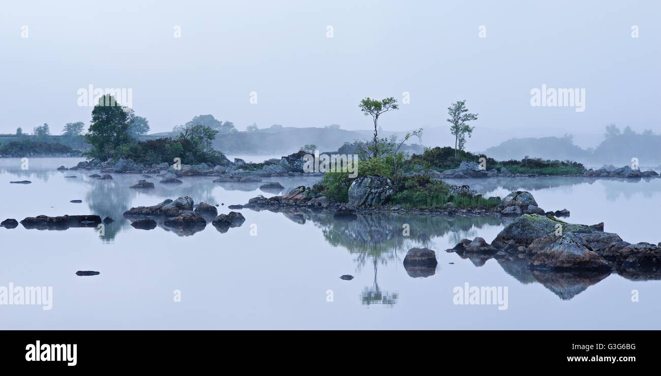 Rannoch Moor in Scotland taken on a foggy still summers morning. The view is of the small islands on Lochan na h-Achlaise Stock Photo