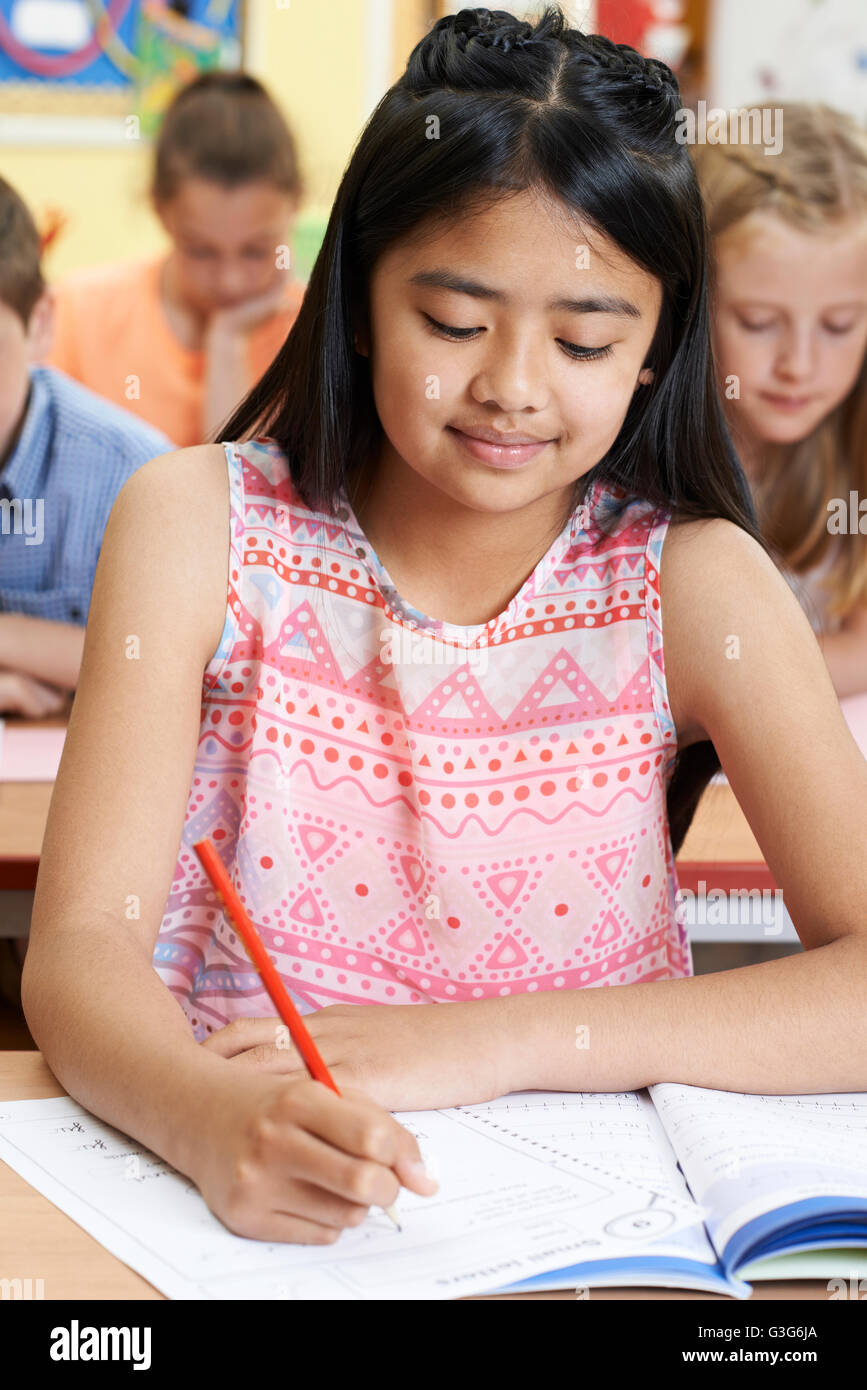 Female Elementary School Pupil Working At Desk Stock Photo