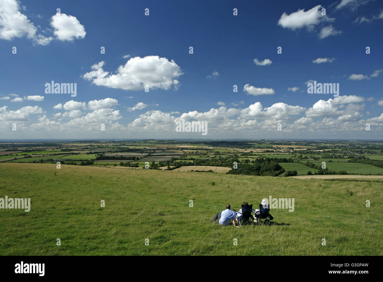 Three people take in the view across Vale of White Horse and a swathe of Oxfordshire from Whitehorse Hill on the Berkshire Downs Stock Photo