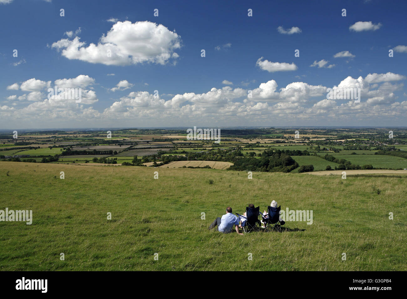 Three people take in the view across Vale of White Horse and a swathe of Oxfordshire from Whitehorse Hill on the Berkshire Downs Stock Photo