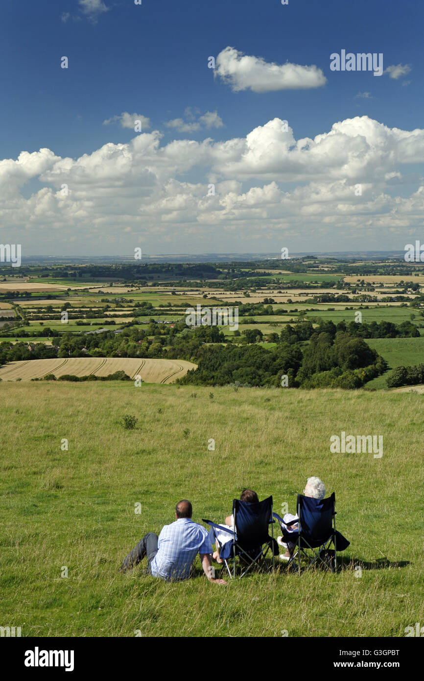 Three people take in the view across Vale of White Horse and a swathe of Oxfordshire from Whitehorse Hill on the Berkshire Downs Stock Photo