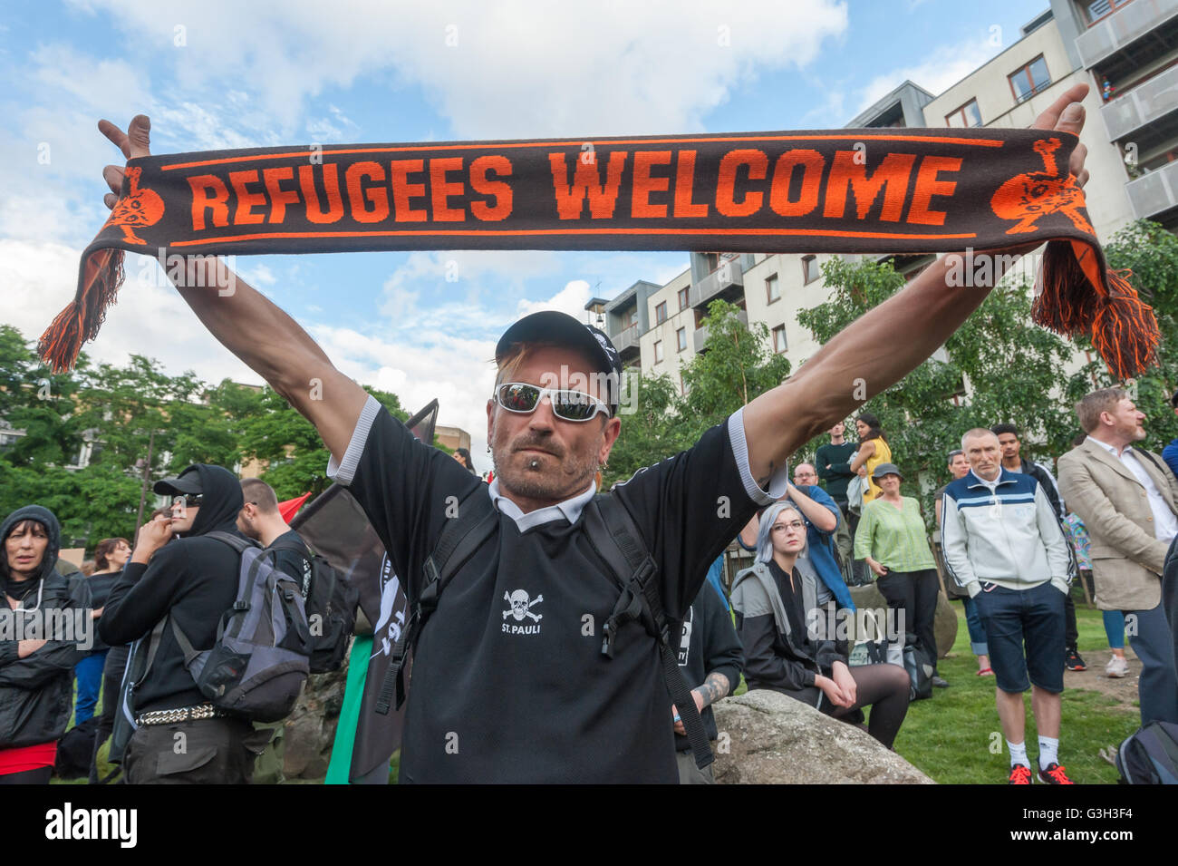 London, UK. June 24th 2016. An anti-fascist protester in a Hamburg St Pauli shirt holds up a scarf with the messge 'Refugees Welcome' at the rally in Altab Ali Park on the day after the UK voted to leave the EU against racism, for migrant rights and against fascist violence. They say that migration and immigrants have been attacked and scapegoated not only by both Remain and Leave campaigns but by mainstream parties and media over more than 20 years, stoking up hatred by insisting immigrants are a 'problem'.Peter Marshall/Alamy Live News Stock Photo