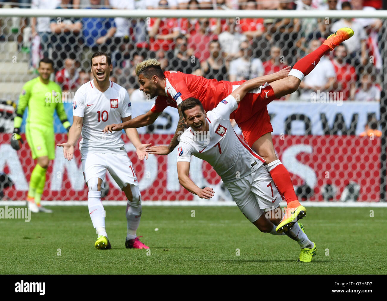 Saint-Etienne, France. 25th June, 2016. Valon Behrami of Switzerland is tripped-up by Arkadiusz Milik of Poland challenge for the ball during the UEFA EURO 2016 Round of 16 soccer match between Switzerland and Poland at the Geoffroy Guichard stadium in Saint-Etienne, France, 25 June 2016. At left is Grzegorz Krychowiak. Photo: Federico Gambarini/dpa/Alamy Live News Stock Photo