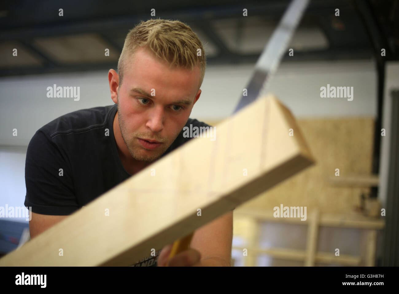 A carpenter trainee saws a beam at the training centre Butzweilerhof in Cologne, germany, 21 June 2016. Photo: Oliver Berg/dpa Stock Photo