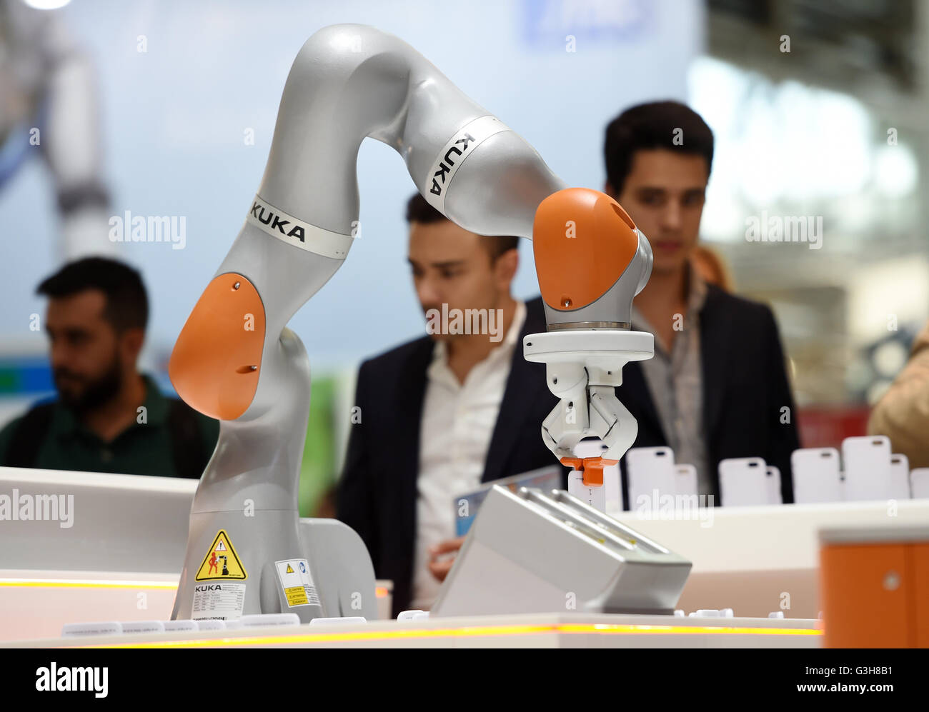 Munich, Germany. 21st June, 2016. Visitors of the robotics fair Automatica look at a roboter at the stall of Kuka in Munich, Germany, 21 June 2016. The fair is open until 24 June 2016. Photo: Tobias Hase/dpa/Alamy Live News Stock Photo