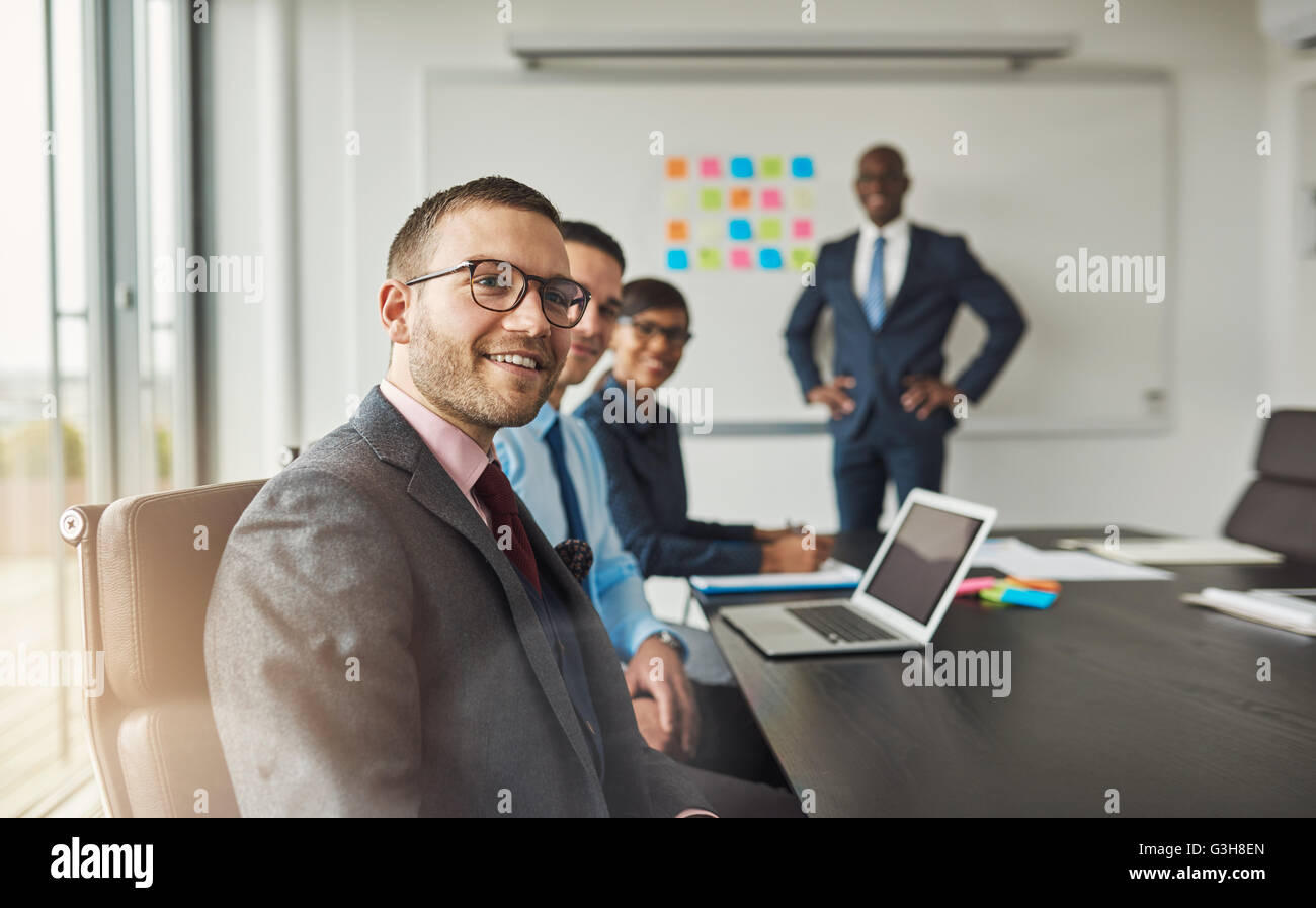 Group of four Black, Hispanic and Caucasian young professional adults in a meeting at their office near large board partially co Stock Photo