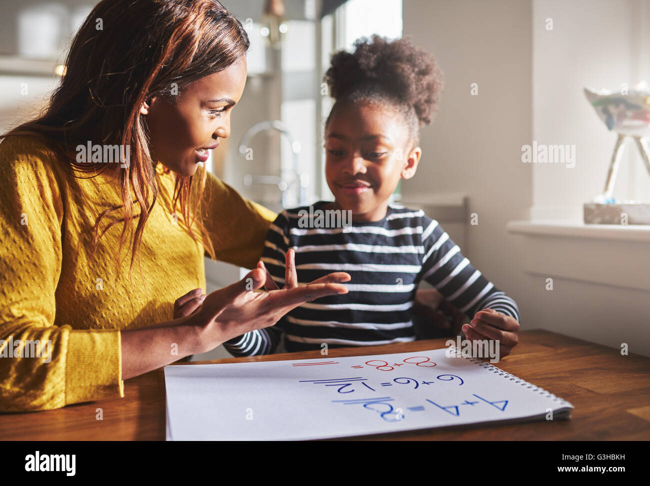 Mom learning daughter to calculate getting ready for school, black family Stock Photo