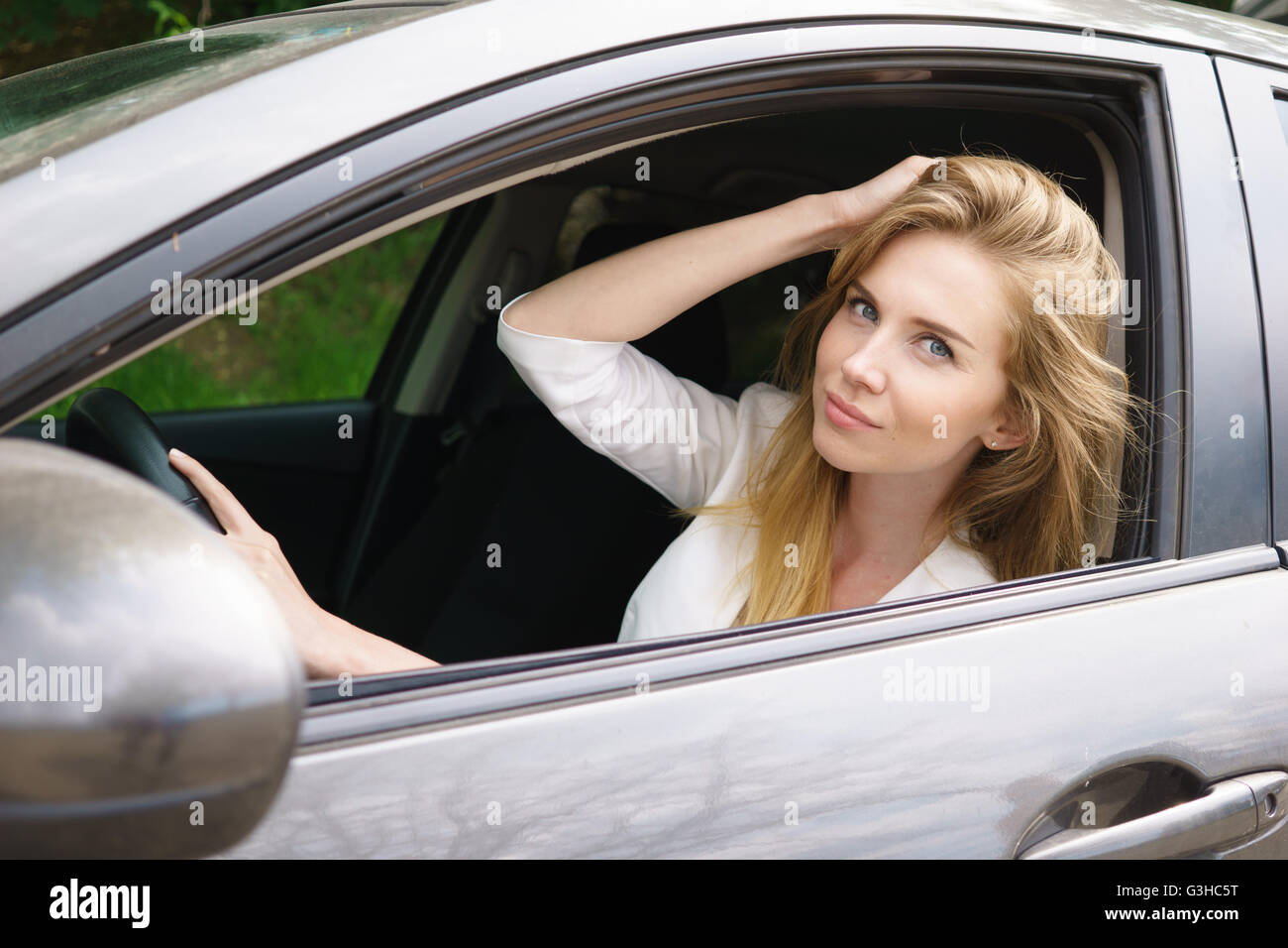 Smiling young bautiful woman sitting in car Stock Photo - Alamy