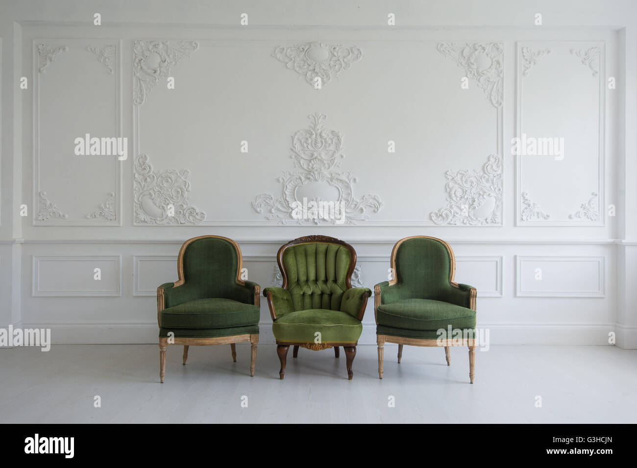 Set Of Green Wooden Vintage Chairs Standing In Front A White Wall