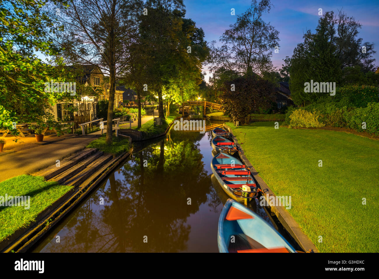 Giethoorn, Netherlands. Giethoorn Punts, or Punters, punting boats for rent in the Dorpsgracht or Village Canal at dusk. Stock Photo