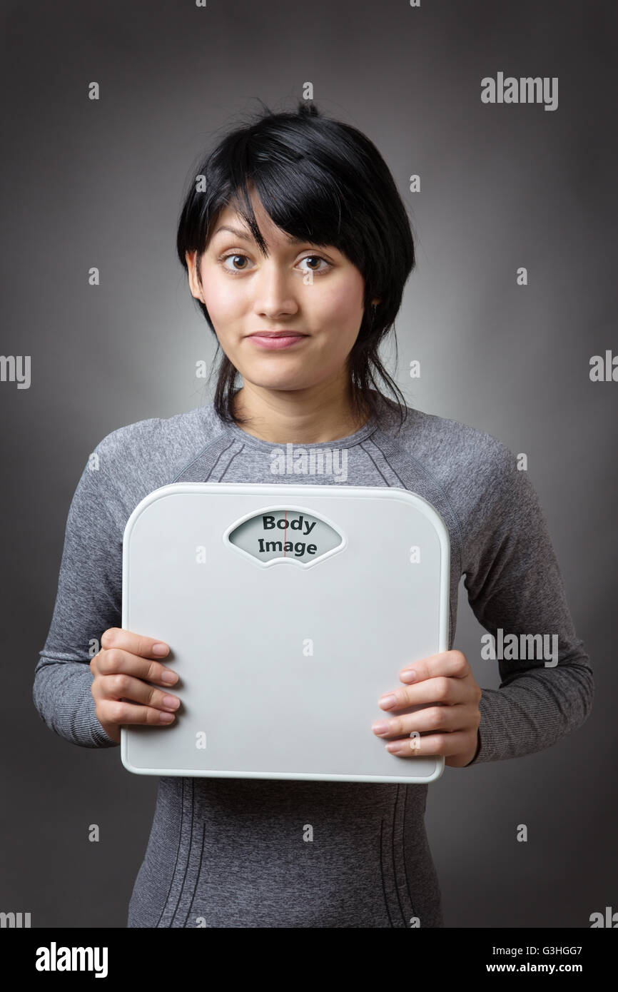 woman holding bathroom scales with the word body image written on the weight dial Stock Photo