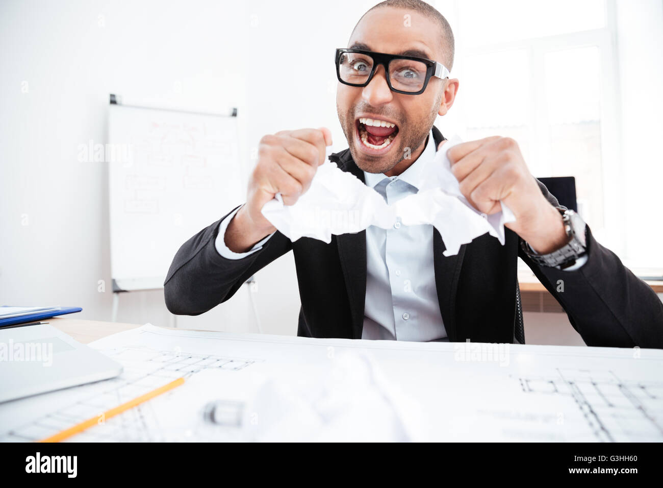 Angry businessman tearing up a document, contract or agreement in ...