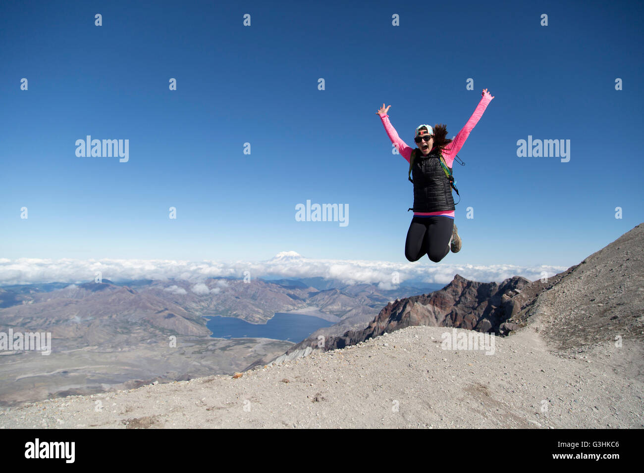 Young woman at mountain top, jumping for joy, Mt. St. Helens, Oregon, USA Stock Photo