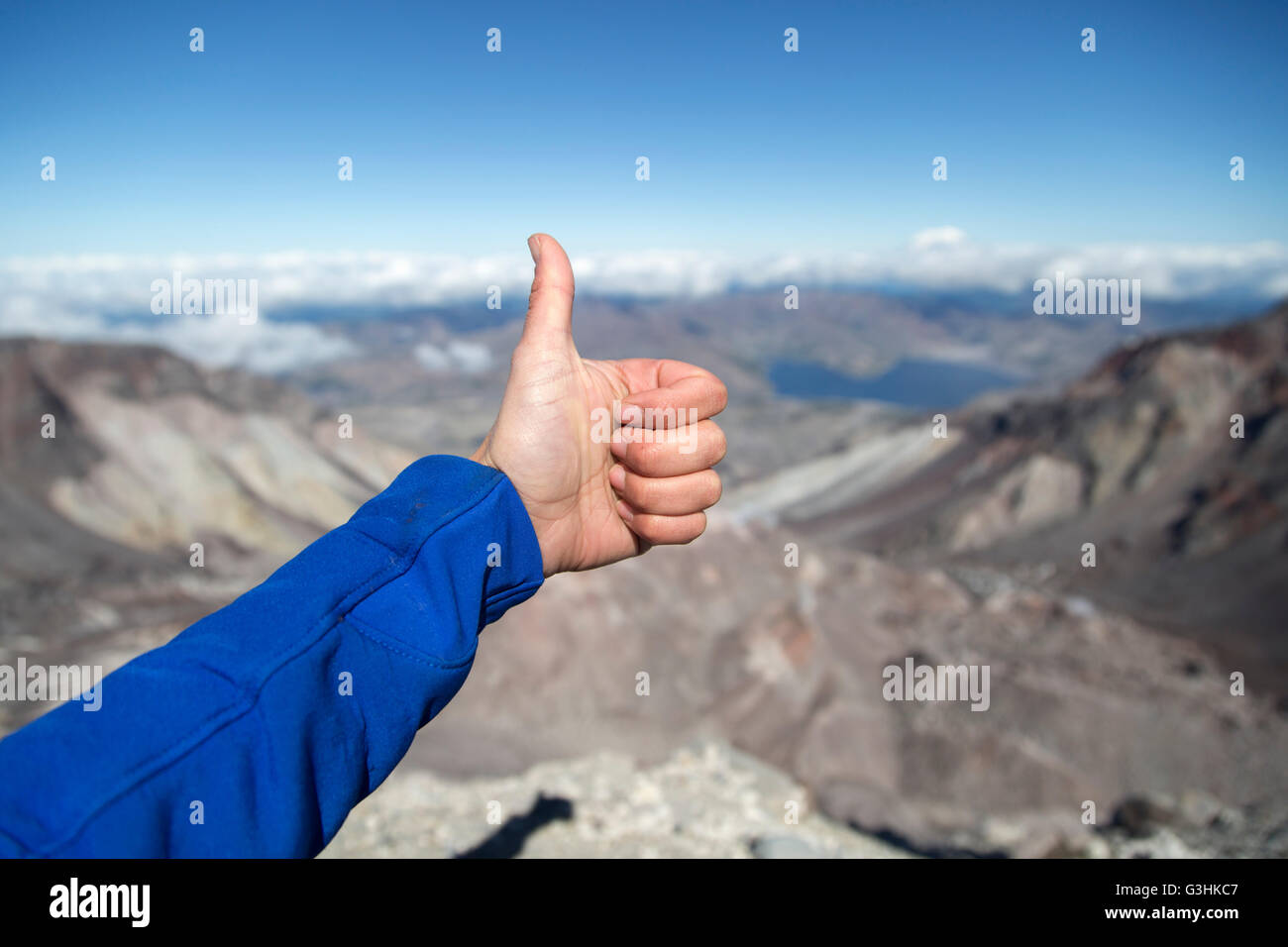 Young woman at mountain top, gesturing thumbs up, focus on hand, Mt. St. Helens, Oregon, USA Stock Photo