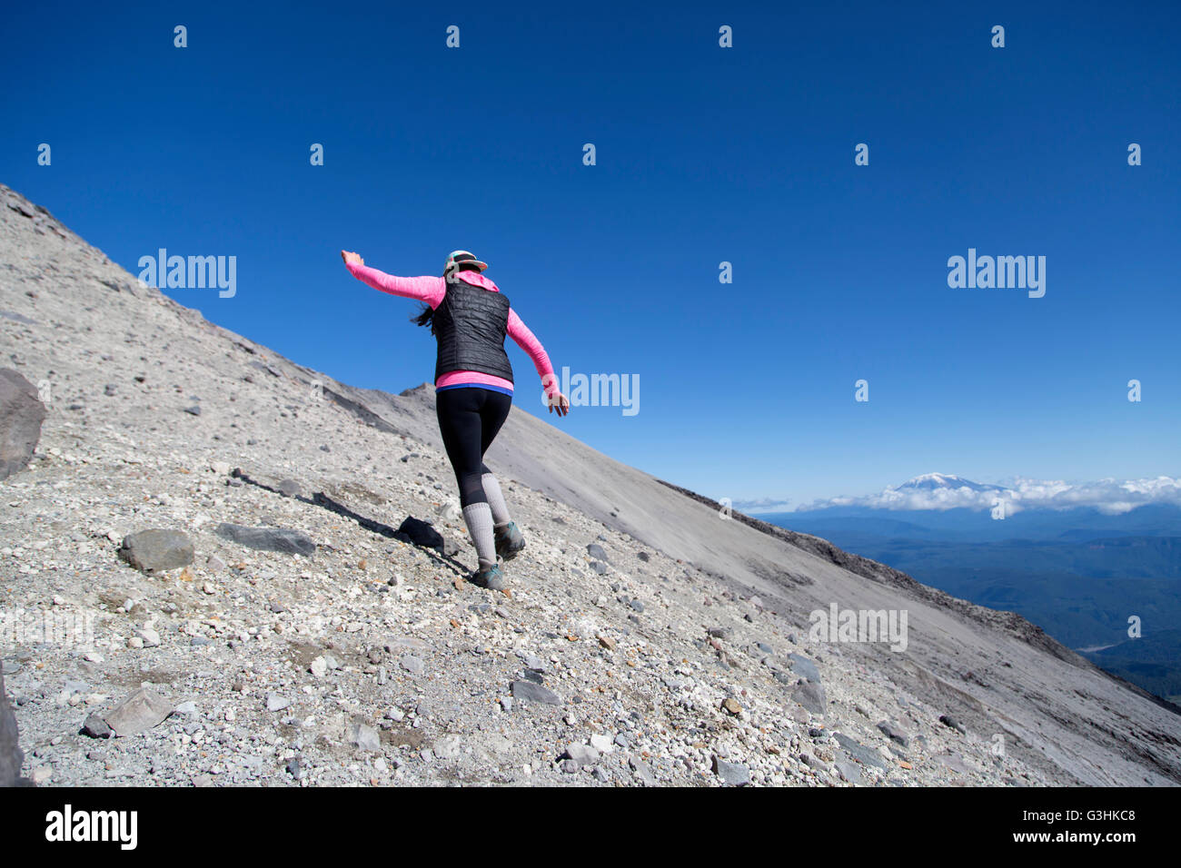 Young woman climbing up side of mountain, rear view, Mt. St. Helens, Oregon, USA Stock Photo