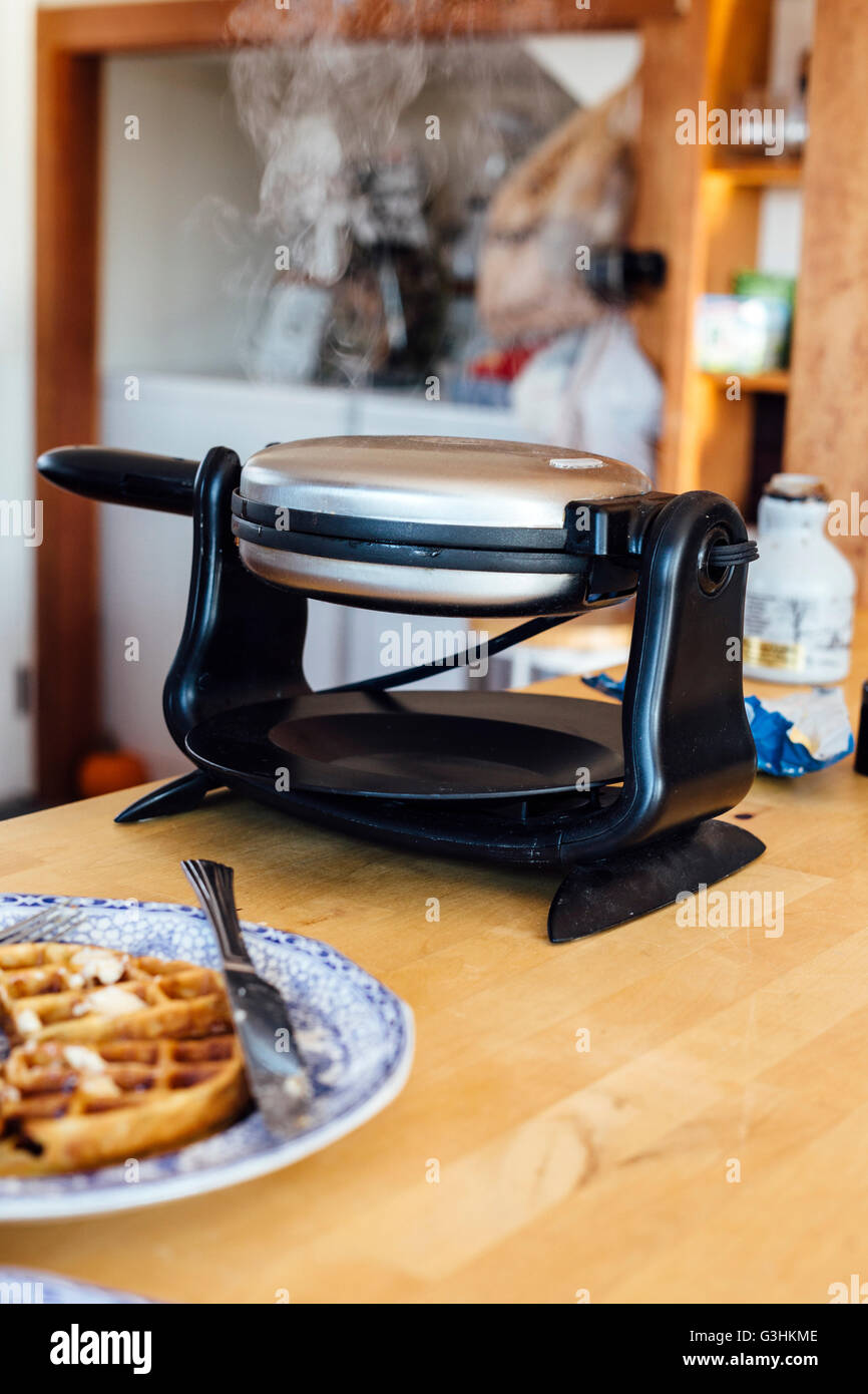 Waffle iron steaming on kitchen counter Stock Photo