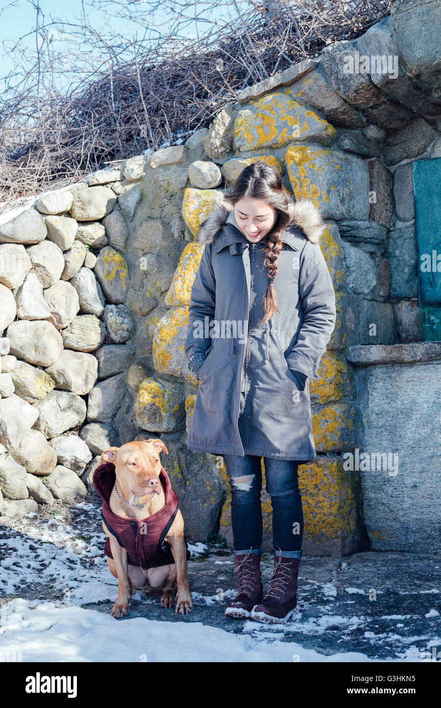Full length view of woman with dog in front of dry stone building Stock Photo