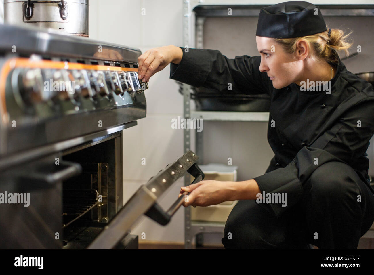 Chef adjusting temperature of oven in kitchen Stock Photo Alamy