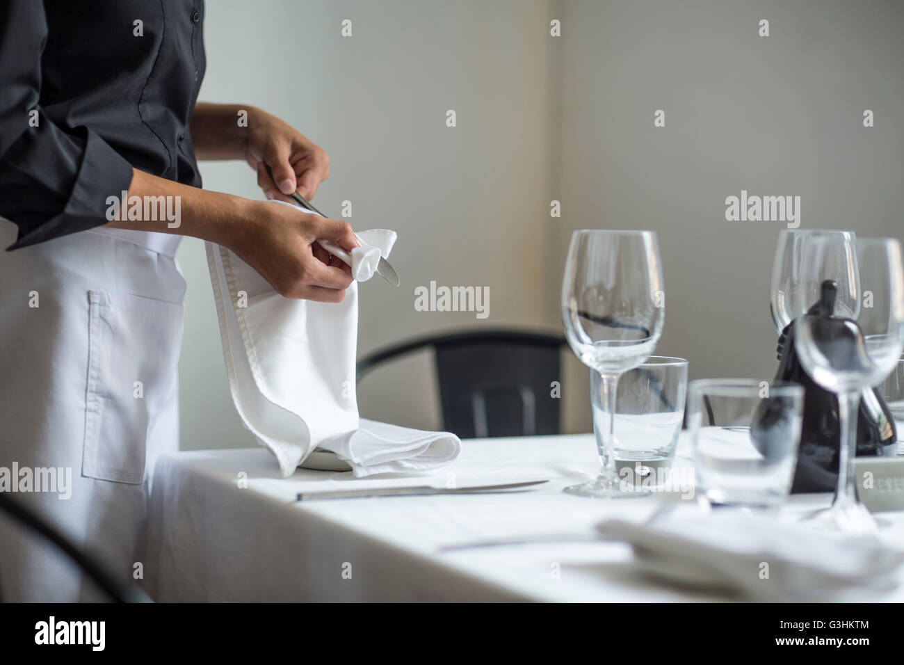 Waitress setting table in restaurant Stock Photo