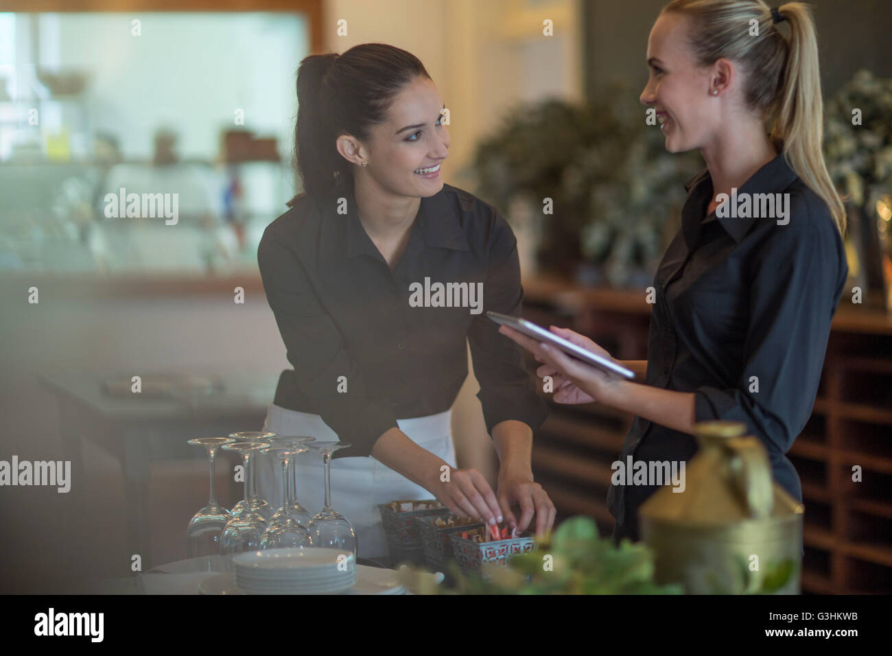 Waitresses chatting and setting table in restaurant Stock Photo
