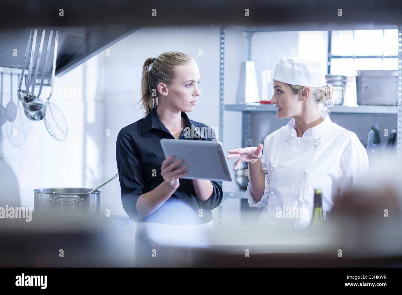 Waitress and chef discussing orders on digital tablet in kitchen Stock Photo