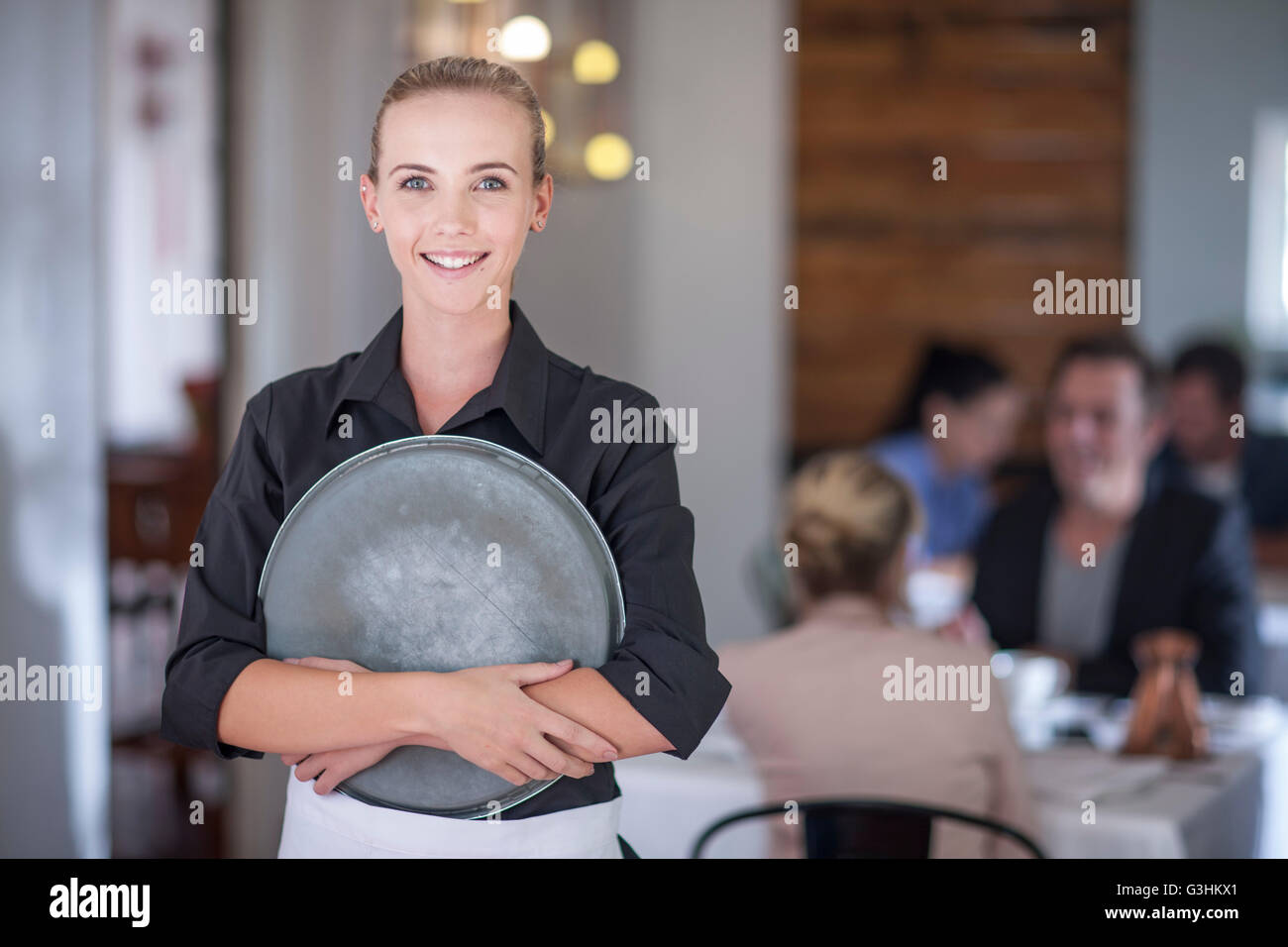 Waitress with serving tray in busy restaurant Stock Photo