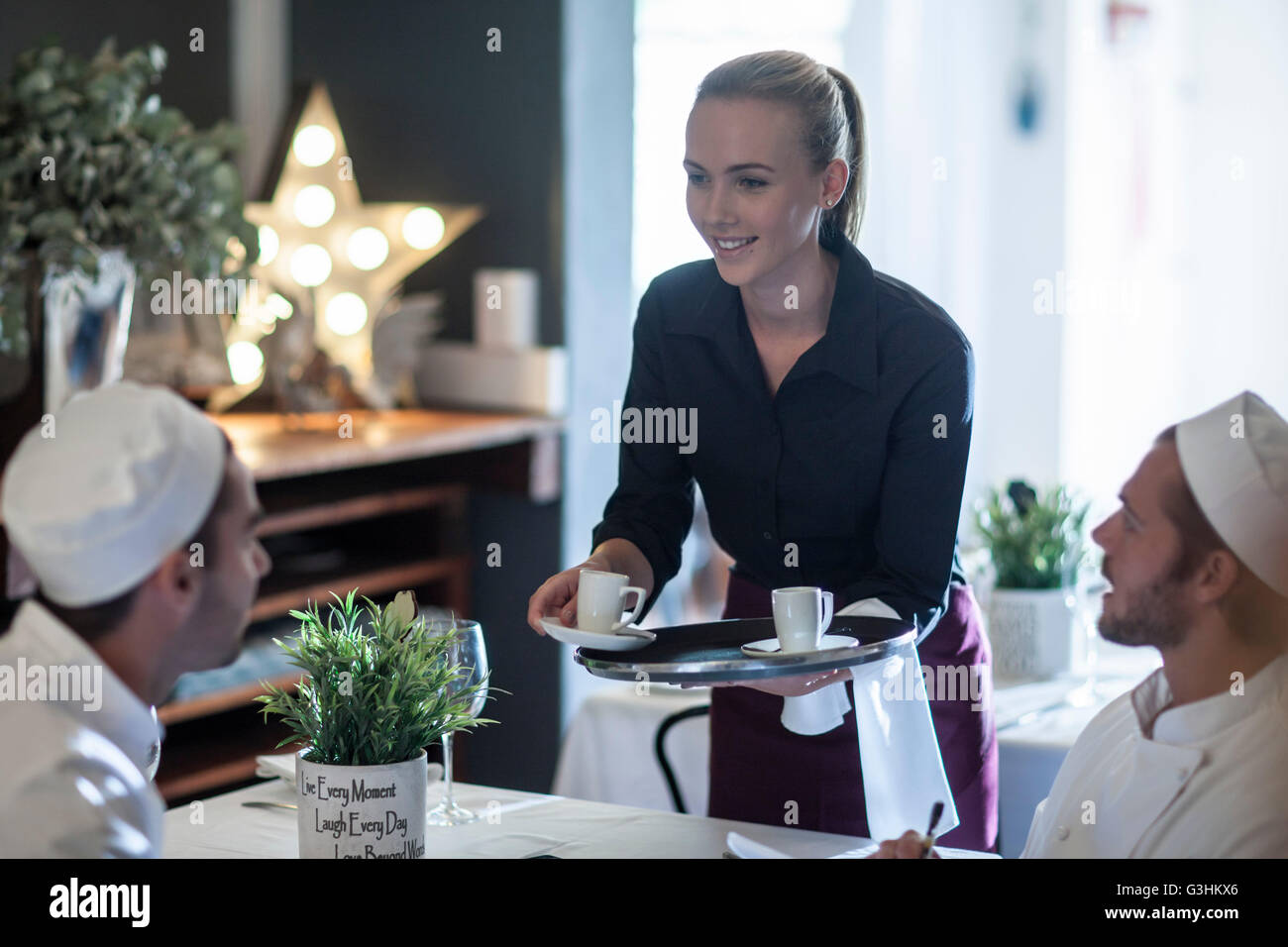 Waitress serving coffee to chefs at break time Stock Photo