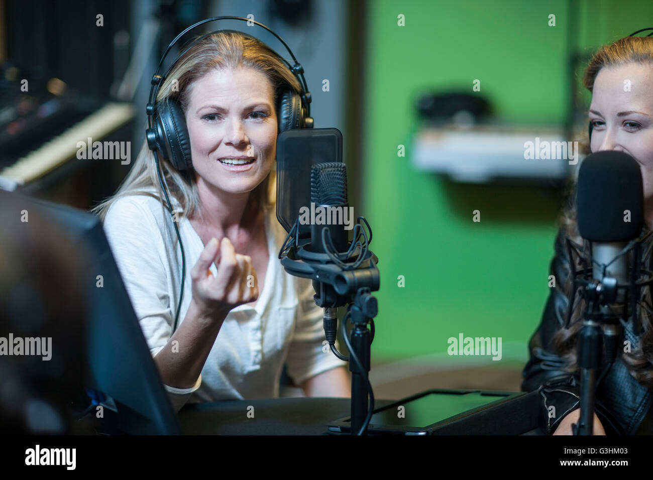 Two musicians in recording studio, wearing headphones, using microphone Stock Photo