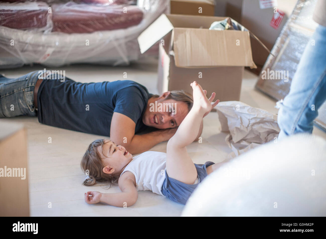 Moving house: father and daughter relaxing on floor of new home Stock Photo