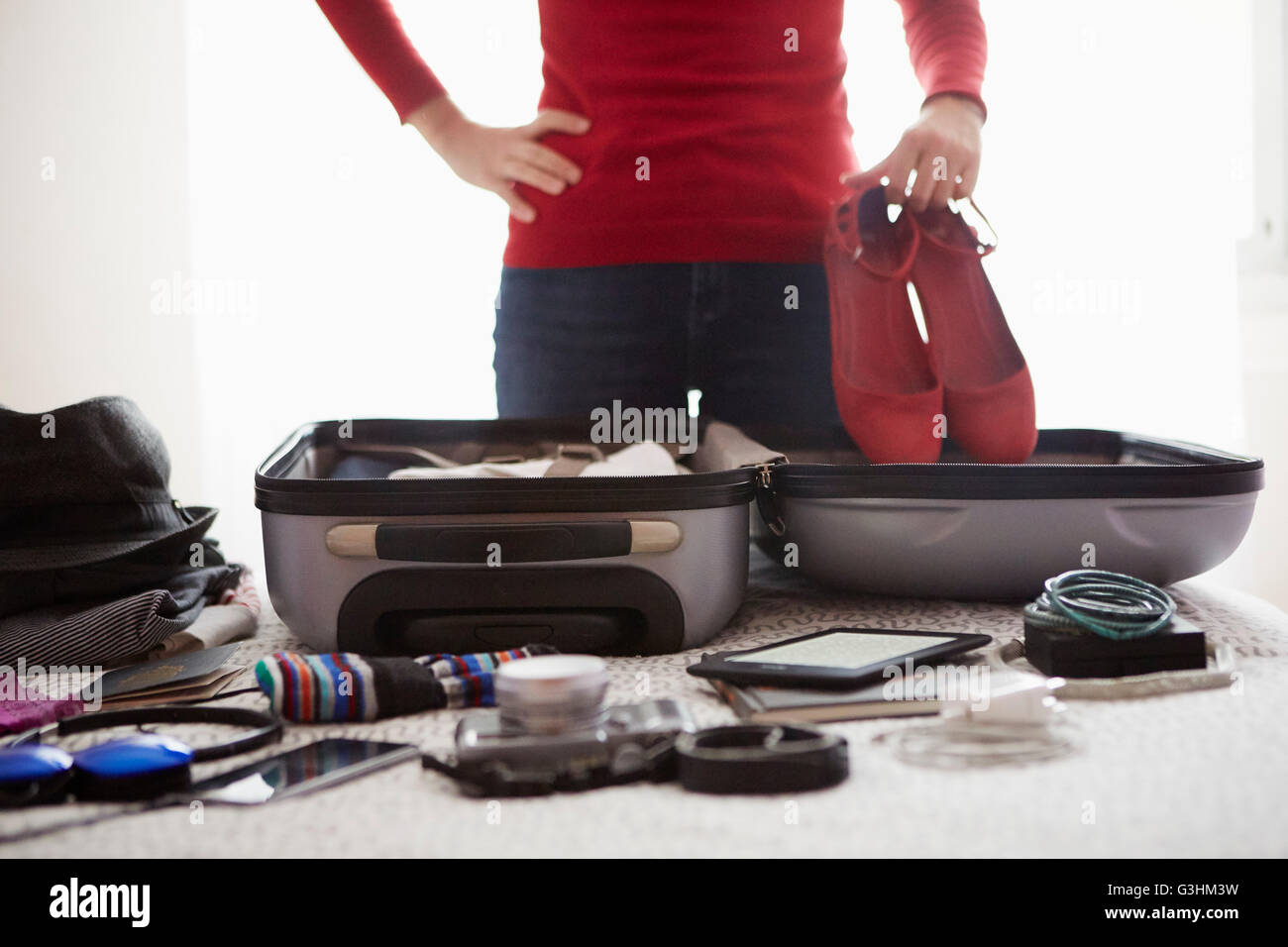 Woman packing suitcase, holding shoes, mid section Stock Photo