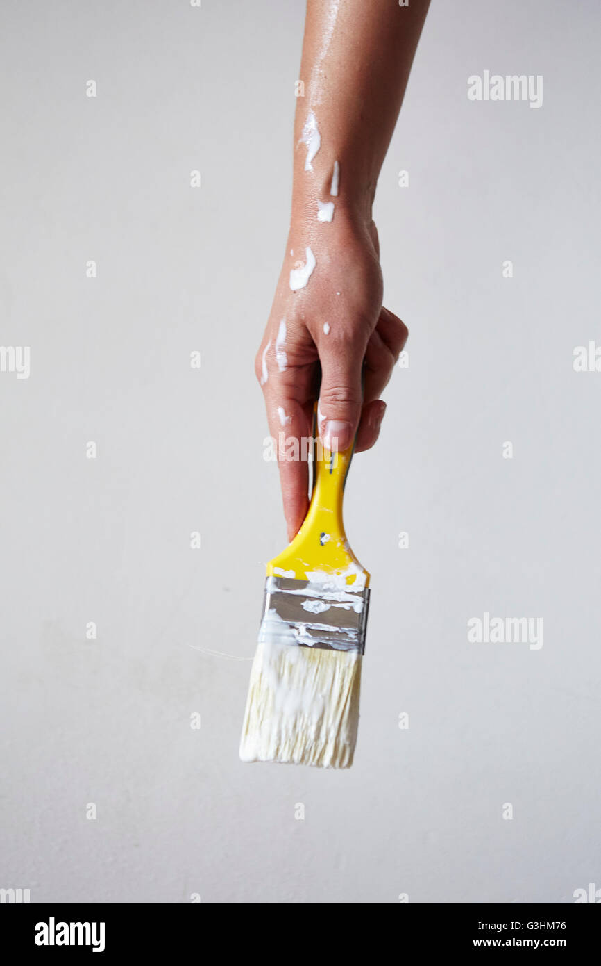 Woman holding paintbrush with white paint, close-up Stock Photo