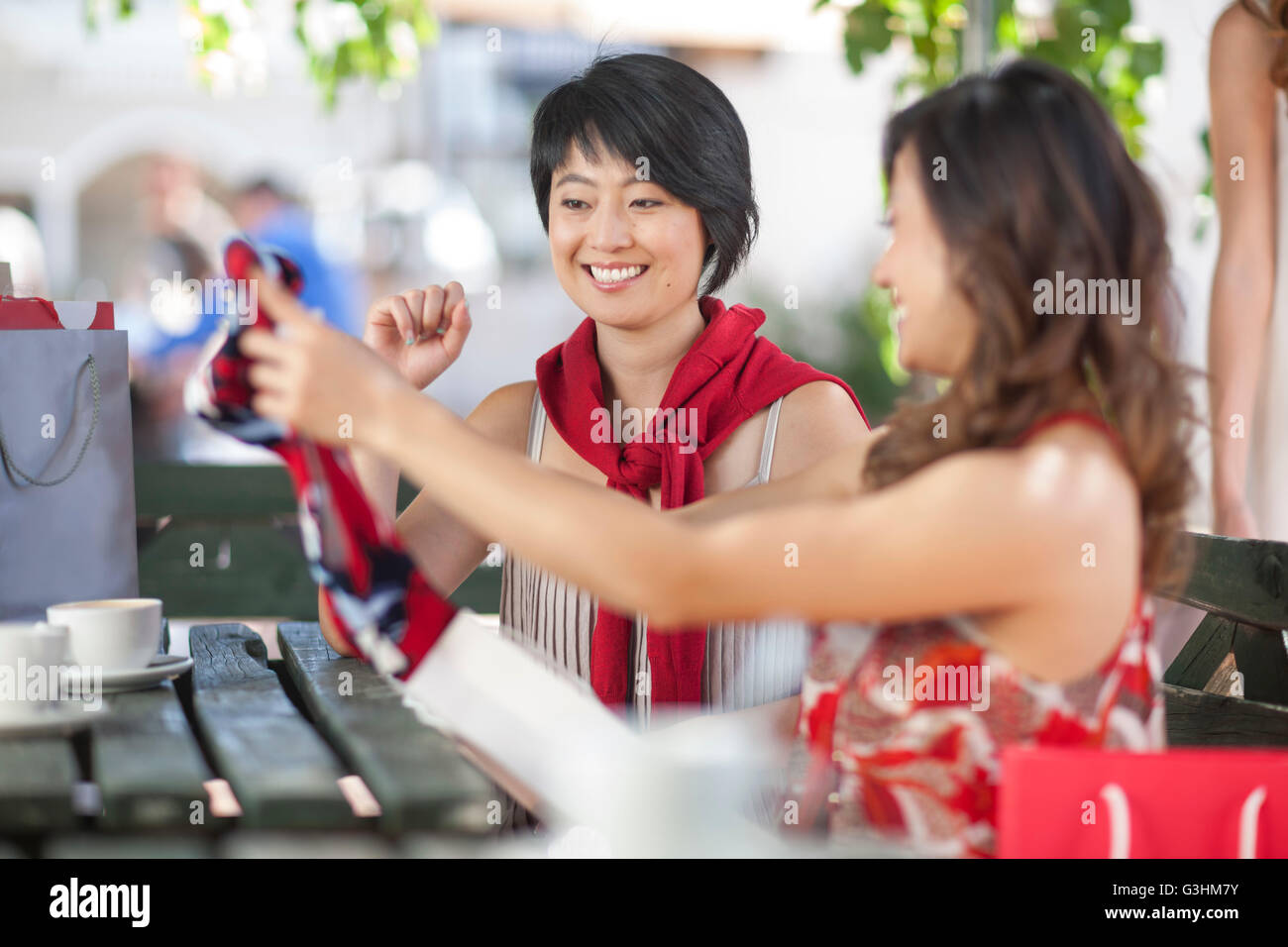 Woman showing friend new dress at city sidewalk cafe Stock Photo
