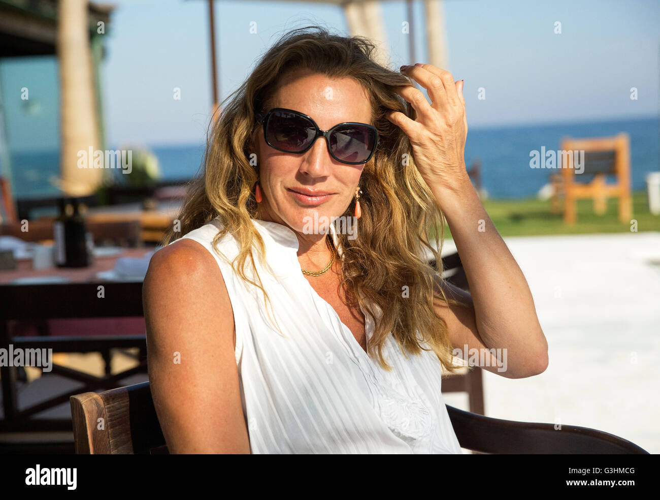 Portrait of mature woman wearing sunglasses at coastal cafe, Spain Stock Photo