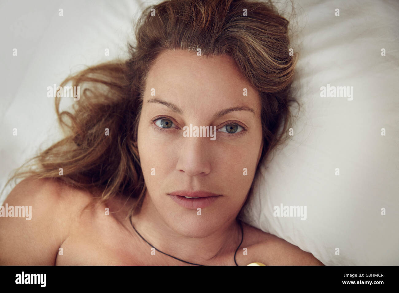Overhead head  and shoulder portrait of beautiful mature woman lying in bed Stock Photo