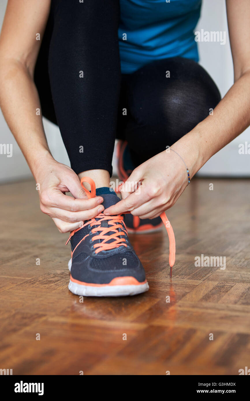 Low section of woman crouching tying shoelace on running shoe Stock Photo
