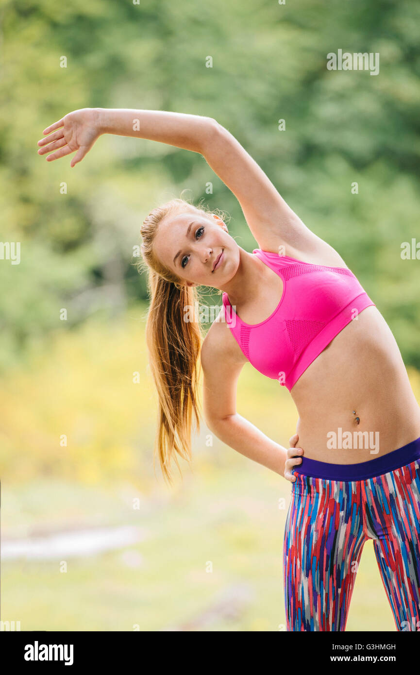 Portrait of teenage girl training, bending sideways in park Stock Photo
