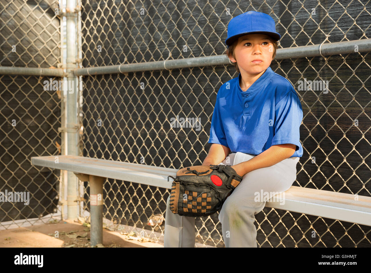 Boy watching from bench at baseball practise Stock Photo
