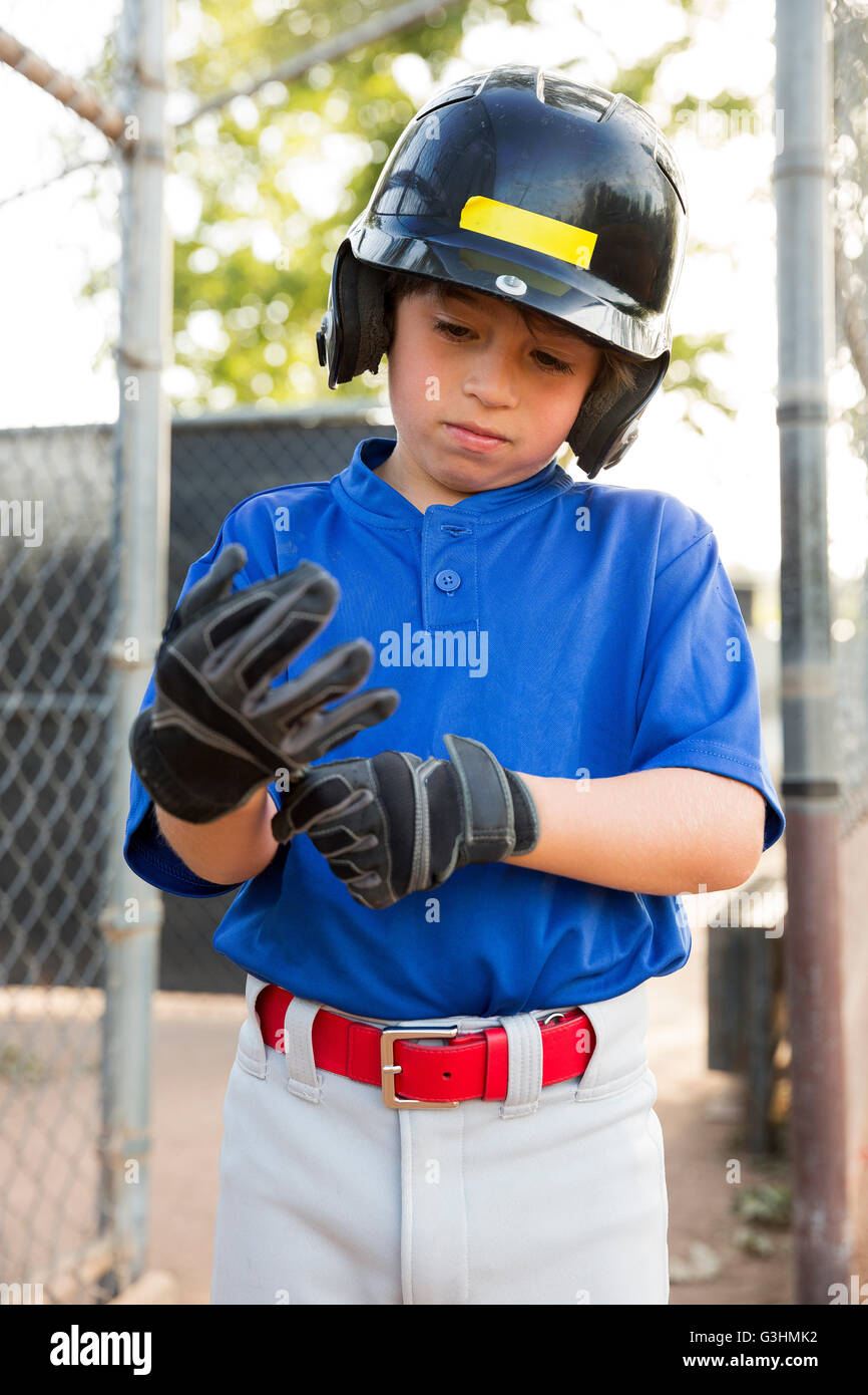 Boy putting on baseball gloves at baseball field Stock Photo Alamy