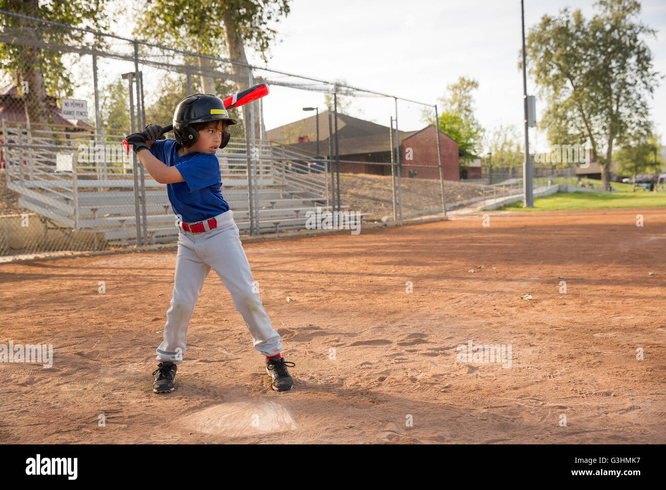 Boy batting at practise on baseball field Stock Photo