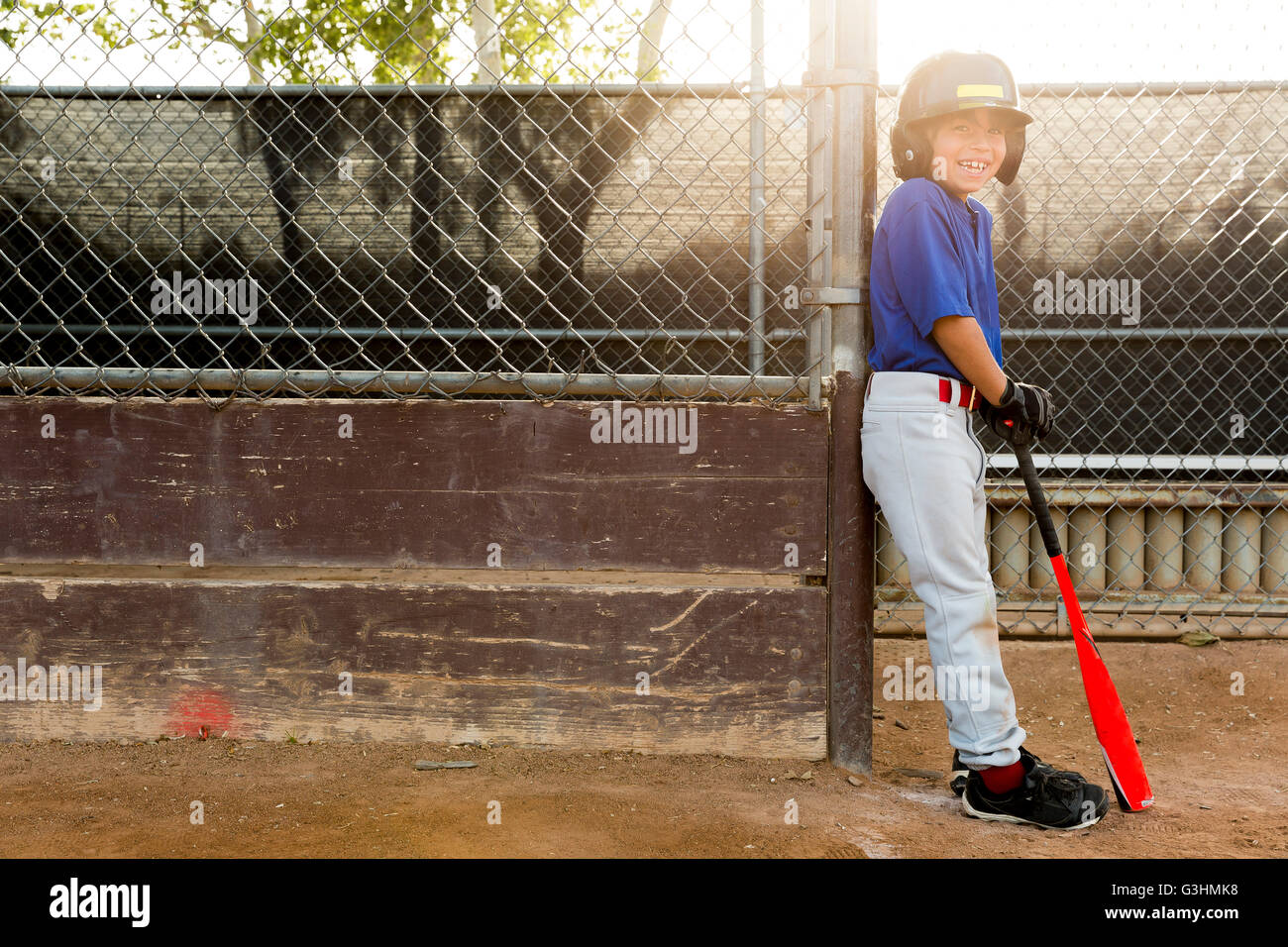 Portrait of boy leaning against fence at baseball practise Stock Photo