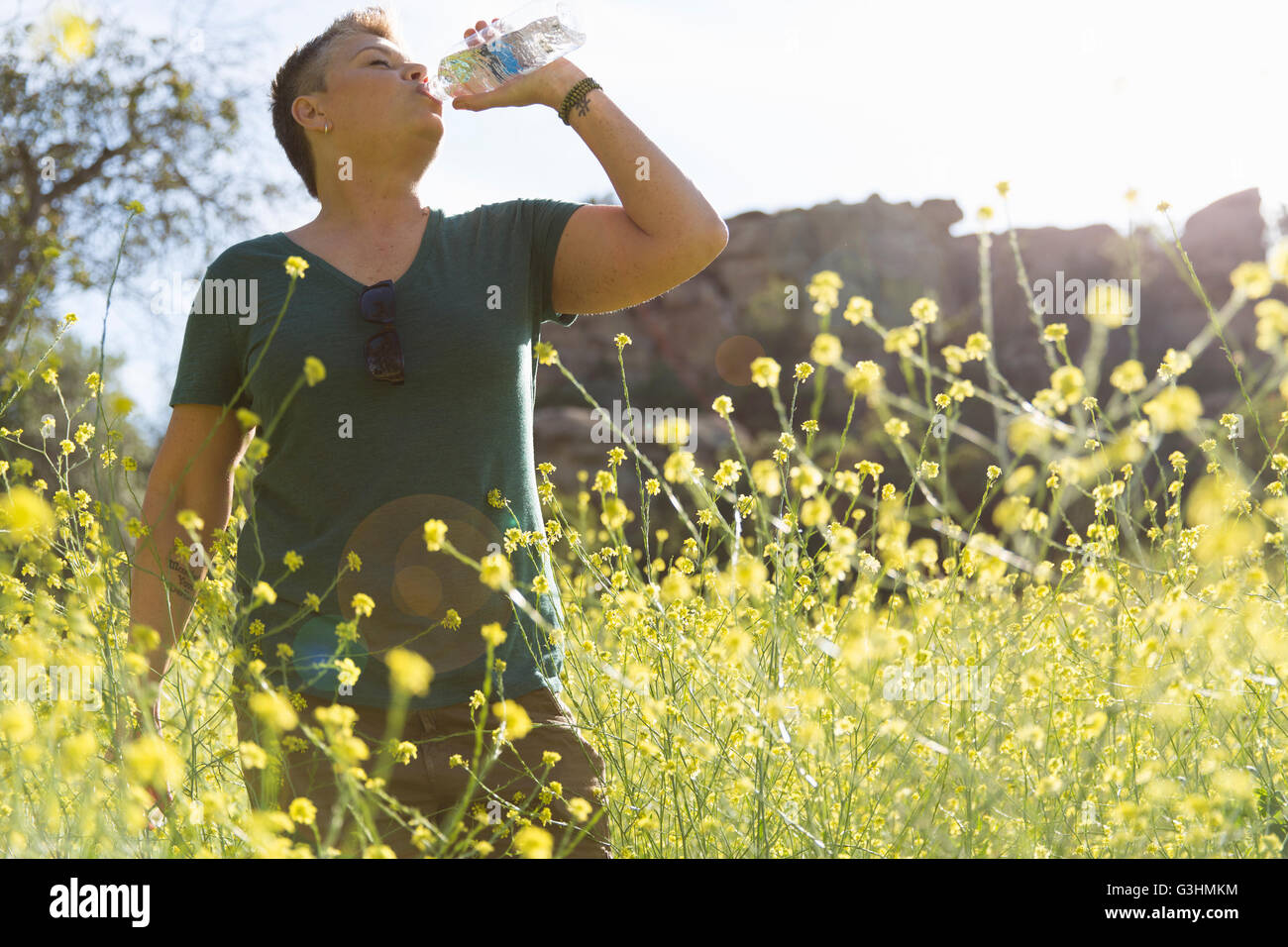 Woman in wildflower meadow drinking water from bottle Stock Photo