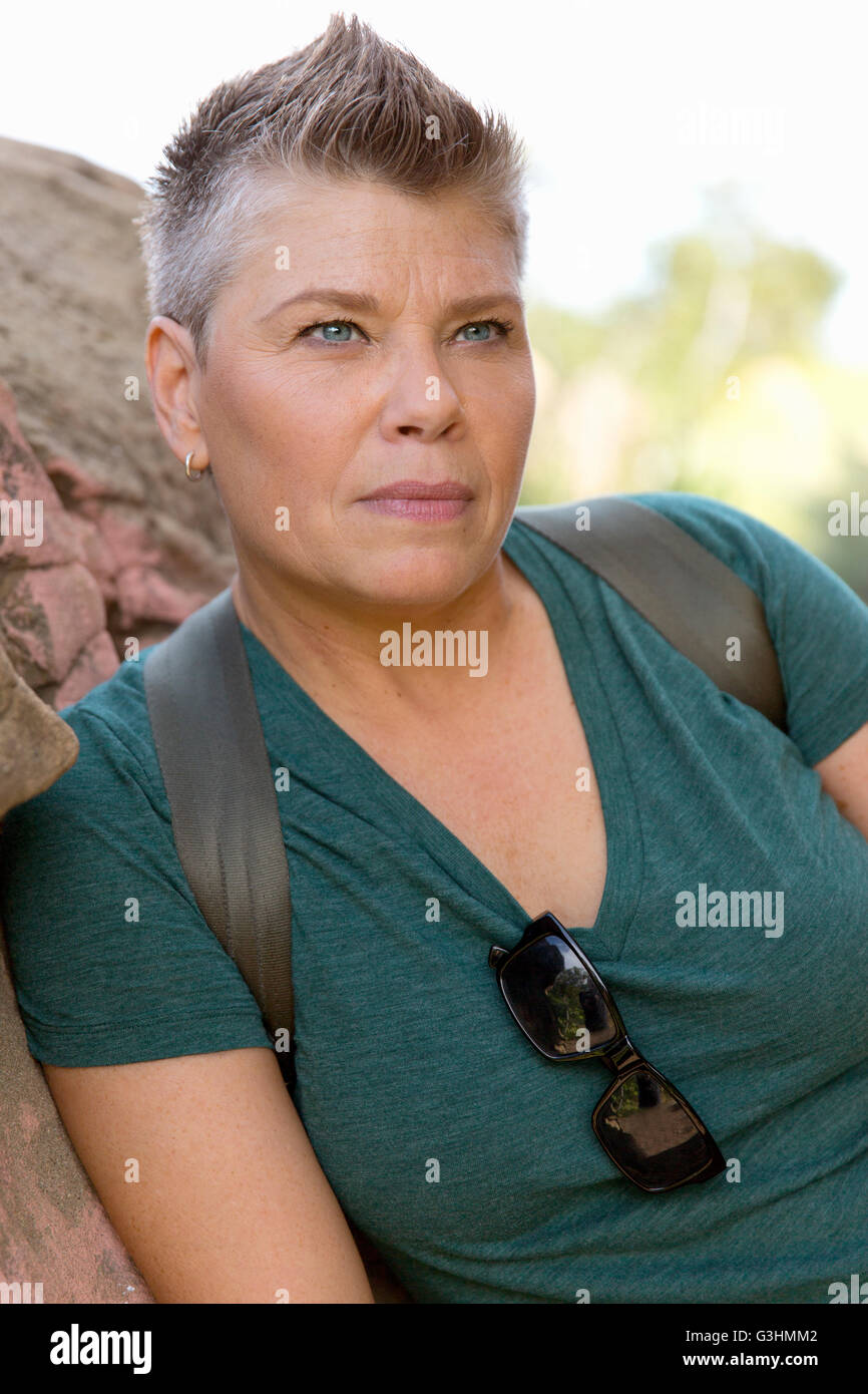 Short haired woman leaning against rock looking away Stock Photo