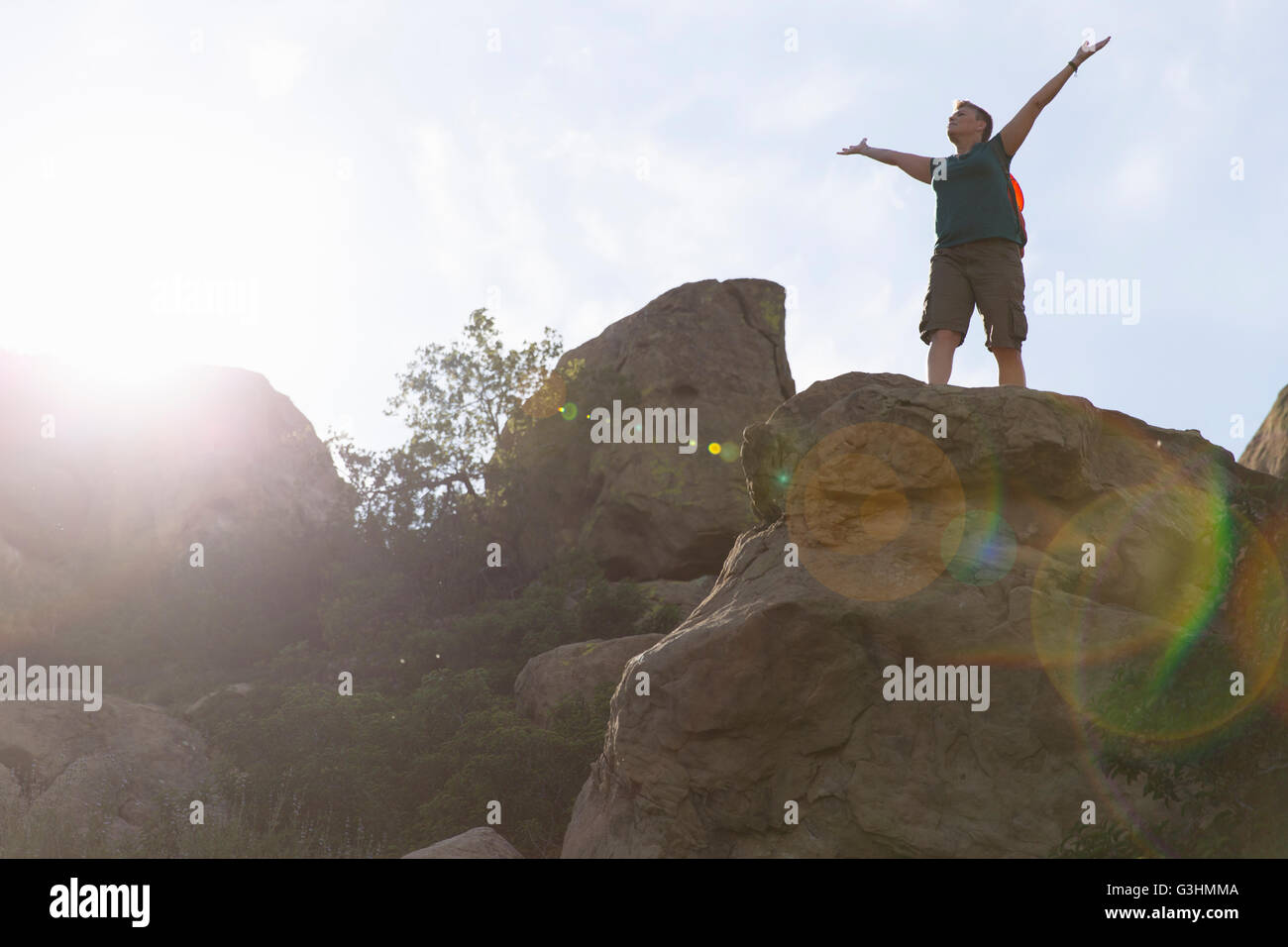Woman hiker on top of rocks arms raised Stock Photo