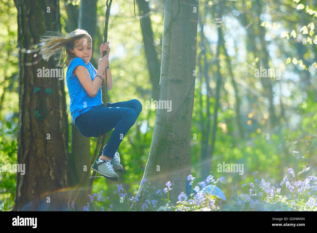 Girl swinging through tree's in bluebell forest, Hallerbos, Brussels, Belgium Stock Photo