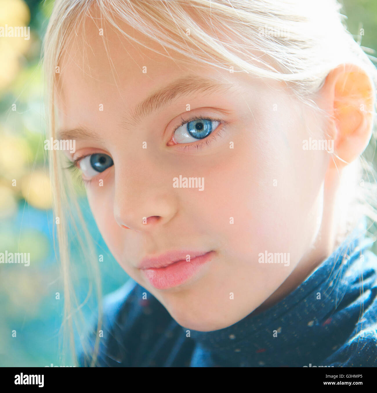 Close up portrait of blond blue eyed girl in garden Stock Photo